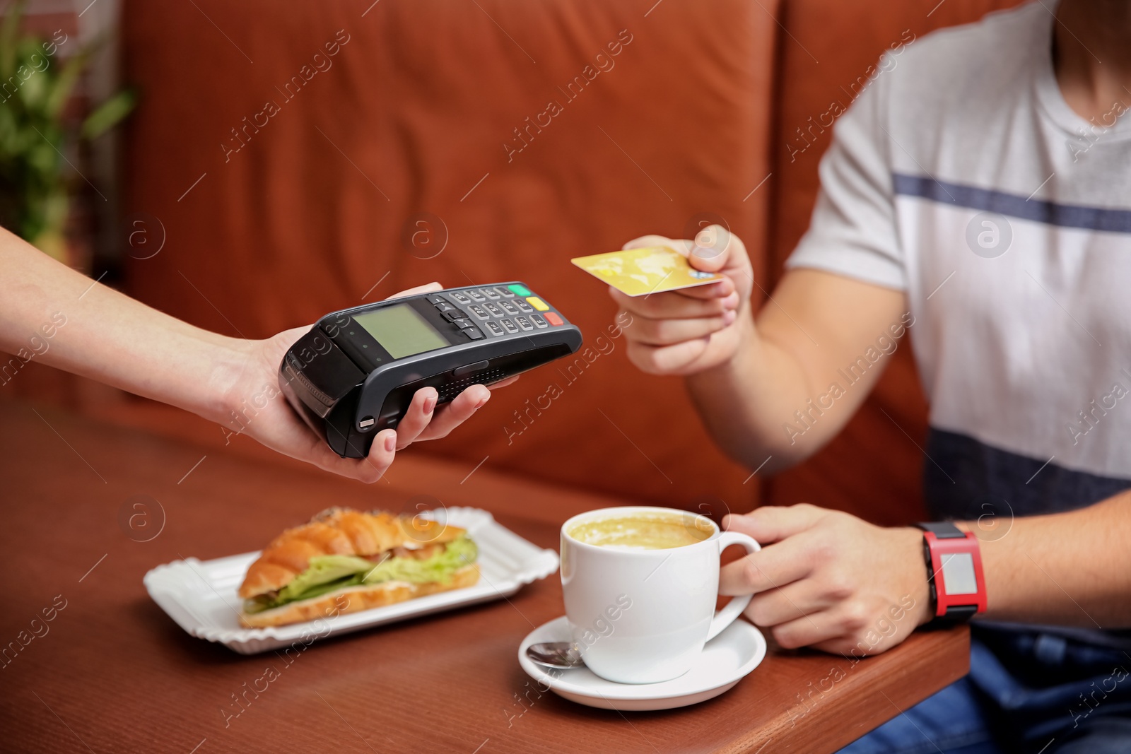 Photo of Man using terminal for credit card payment in cafe, closeup