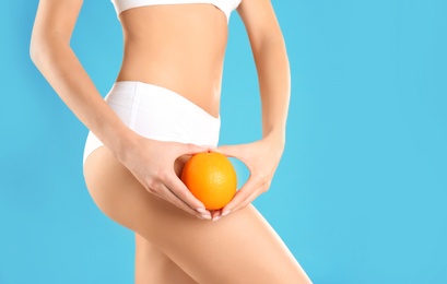 Photo of Closeup view of slim woman in underwear with orange on color background, space for text. Cellulite problem concept