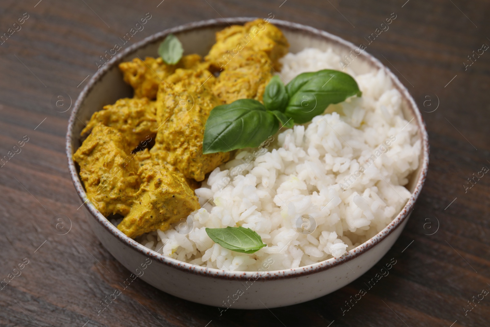 Photo of Delicious rice and chicken with curry sauce on wooden table, closeup