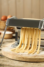 Photo of Pasta maker with raw dough on wooden table