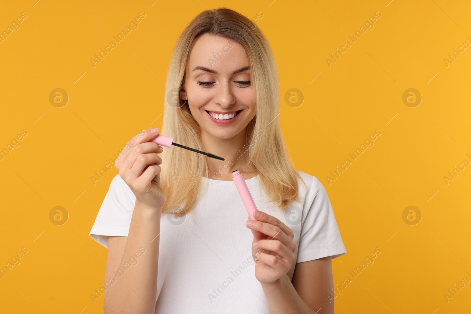 Photo of Beautiful woman with mascara on orange background