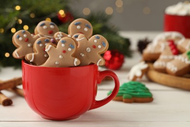 Photo of Delicious homemade Christmas cookies in cup on white wooden table against blurred festive lights. Space for text