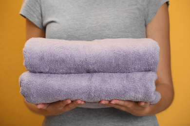 Woman holding fresh towels on orange background, closeup