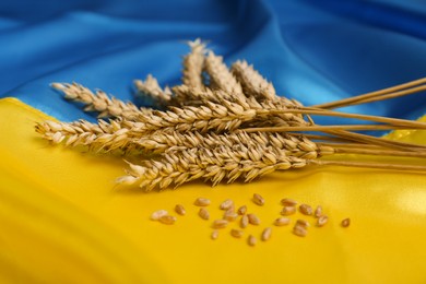 Ears of wheat and grains on Ukrainian national flag, closeup