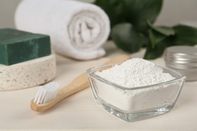 Photo of Tooth powder and brush on white wooden table, closeup
