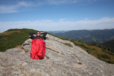 Photo of Tourist in sleeping bag on mountain peak