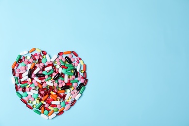 Photo of Heart made of pills on color background, top view with space for text. Cardiology concept