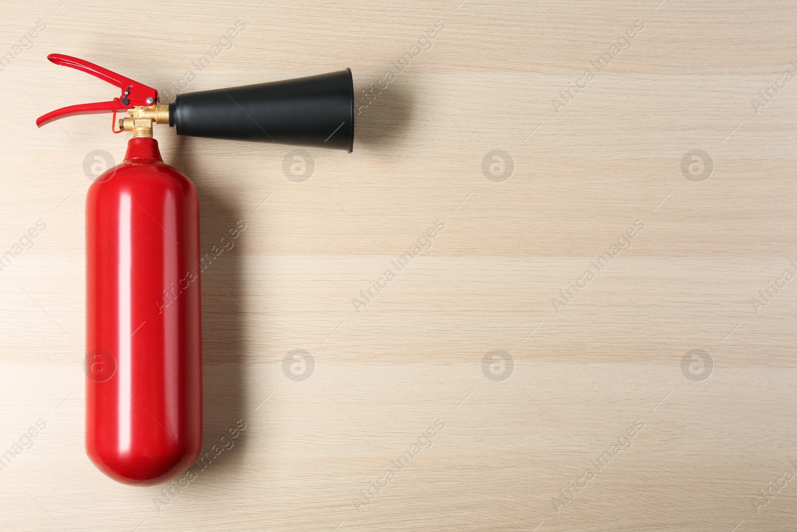 Photo of Fire extinguisher on wooden background, top view. Space for text