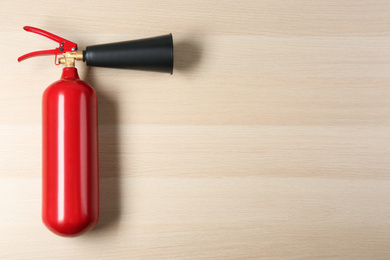 Fire extinguisher on wooden background, top view. Space for text