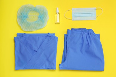 Photo of Flat lay composition with medical uniform and face mask on yellow background