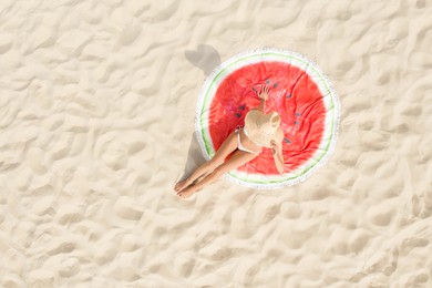 Woman sunbathing on round beach towel at sandy coast, aerial view. Space for text