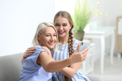 Happy mother and daughter taking selfie at home