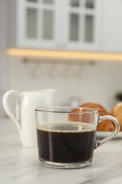 Photo of Aromatic coffee in glass cup on white marble table, space for text