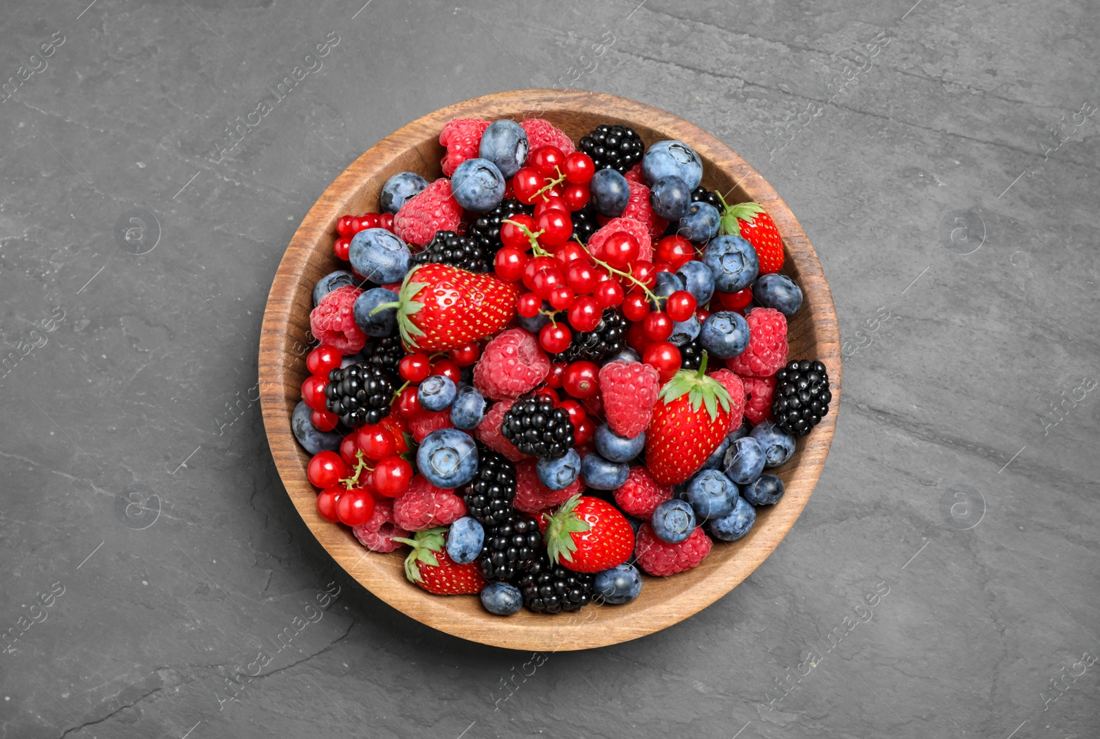 Photo of Mix of different fresh berries in bowl on grey table, top view