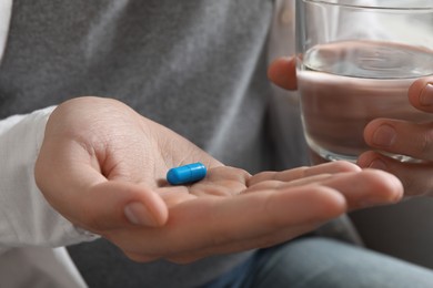 Man with glass of water and pill, closeup