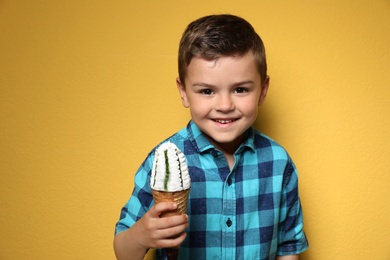 Photo of Adorable little boy with delicious ice cream against color background