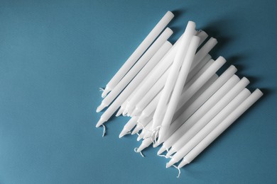 Photo of Many church wax candles on light blue background, flat lay and space for text