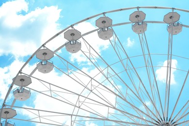 Photo of Large observation wheel against blue cloudy sky, low angle view