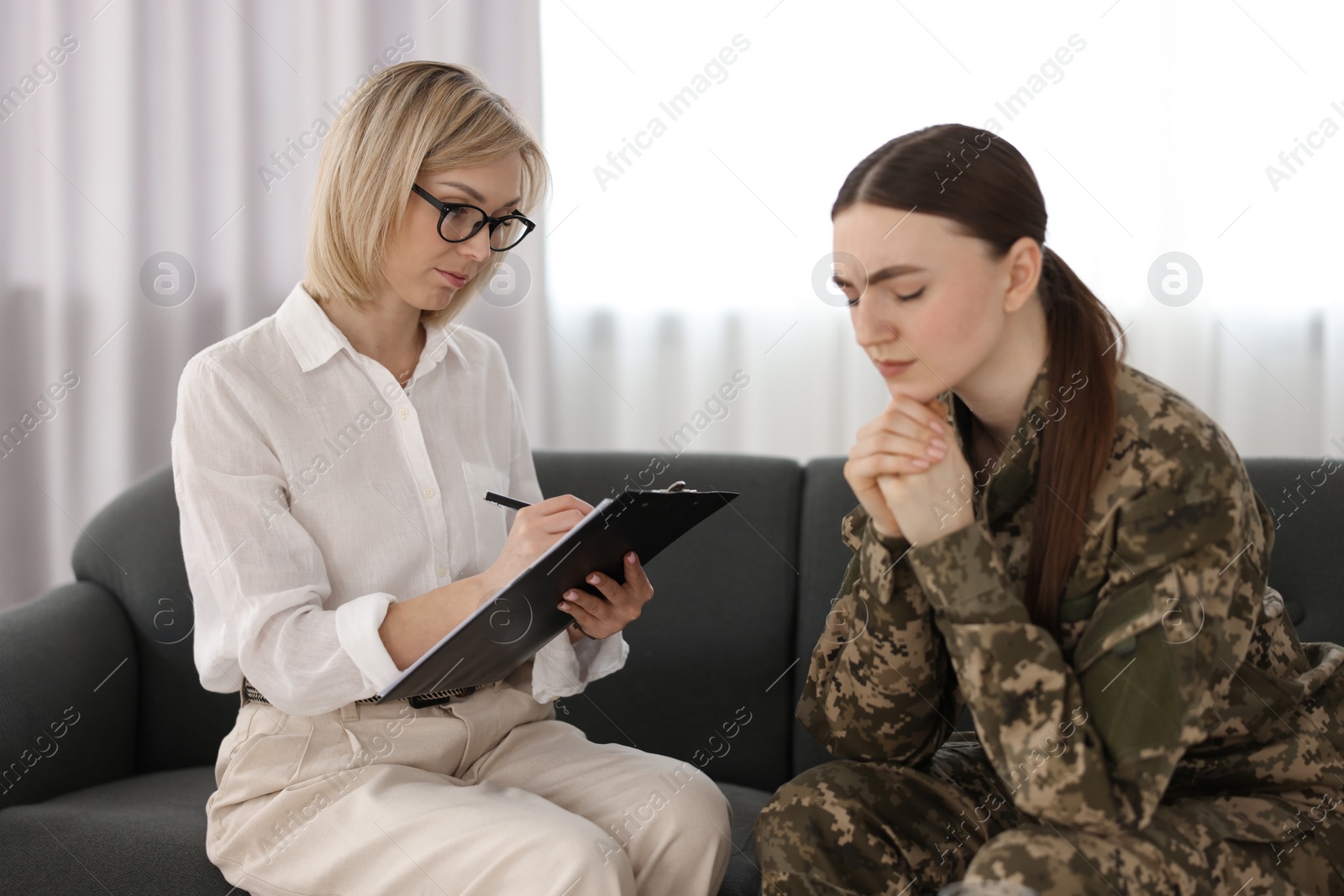 Photo of Psychotherapist working with military woman on sofa in office