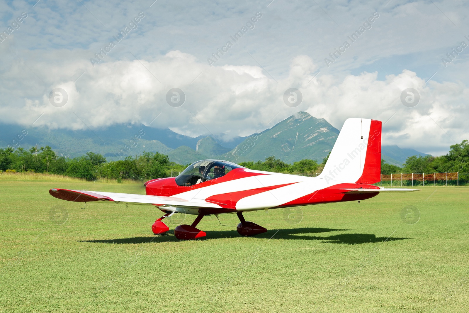 Photo of Modern airplane on green grass against mountains background