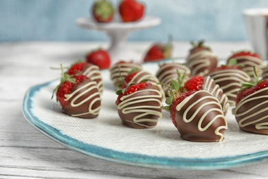 Photo of Plate with chocolate covered strawberries on table, closeup