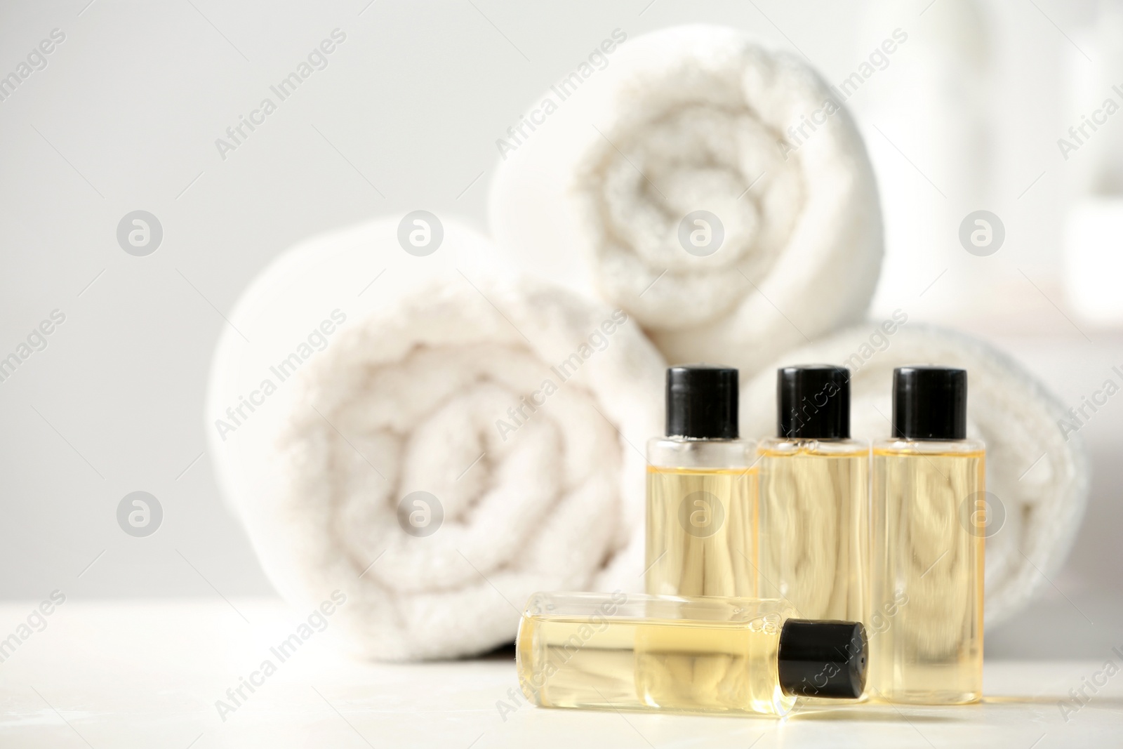 Photo of Mini bottles with cosmetic products and towels on table, space for text. Hotel amenities