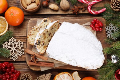 Photo of Traditional Christmas Stollen with icing sugar on wooden table, flat lay