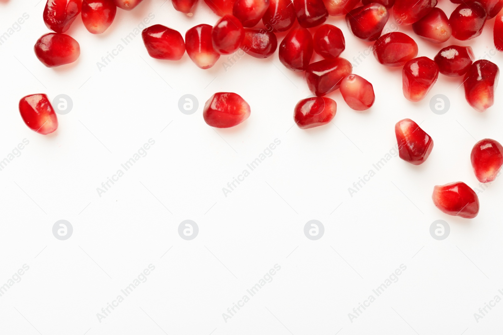 Photo of Many ripe juicy pomegranate grains on white background, flat lay. Space for text