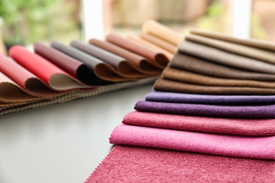 Fabric and leather samples of different colors for interior design on table