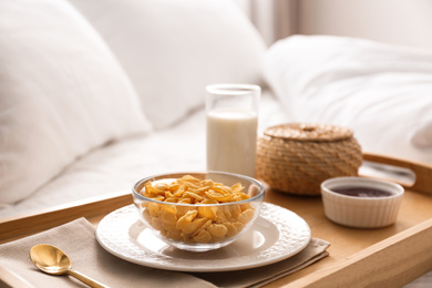 Photo of Corn flakes and milk in tray on bed.  Delicious morning meal