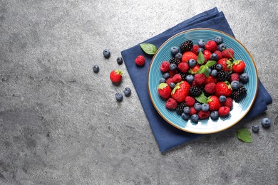 Photo of Many different fresh ripe berries in plate on grey table, flat lay. Space for text