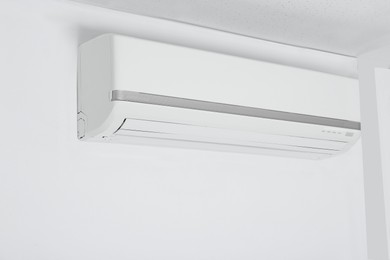 Photo of Modern air conditioner hanging on white wall
