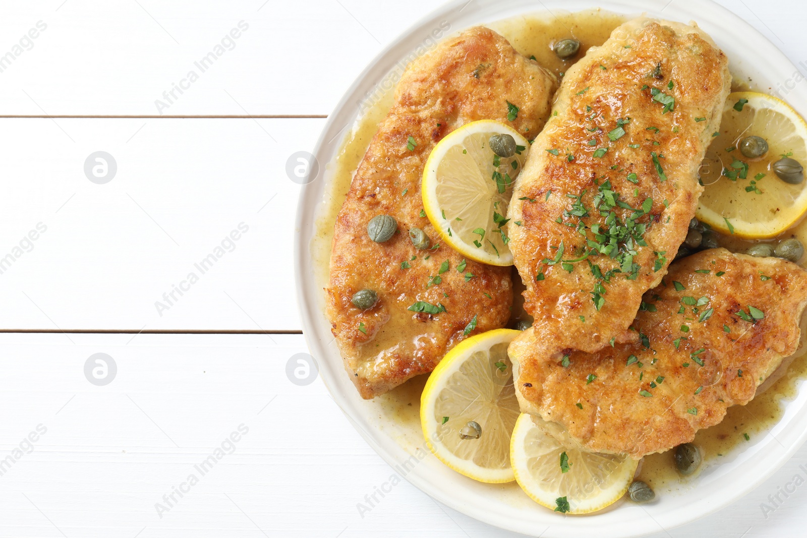 Photo of Delicious chicken piccata on white wooden table, top view. Space for text