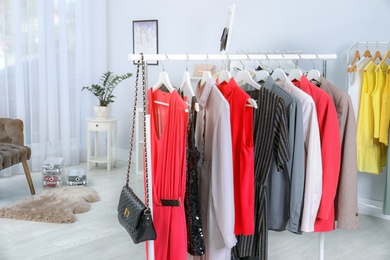 Wardrobe racks with different stylish clothes in light room