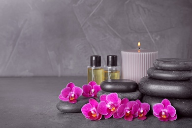 Photo of Composition with spa stones and orchid flowers on grey background. Space for text