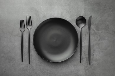 Empty plate and cutlery on grey table, flat lay