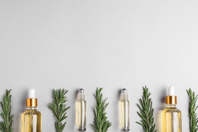 Flat lay composition with rosemary essential oil and space for text on light background
