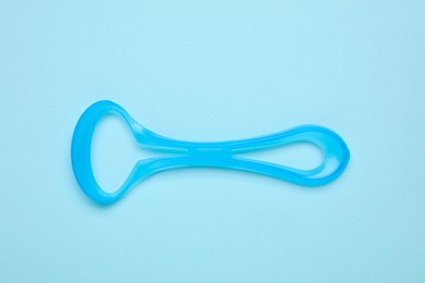 Photo of Tongue cleaner on light blue background, top view