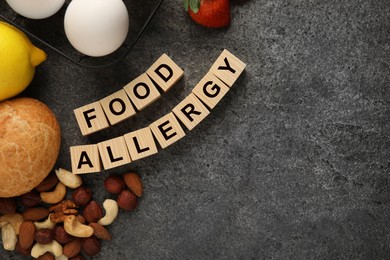 Image of Food allergy. Different fresh products and wooden cubes on grey table, flat lay with space for text