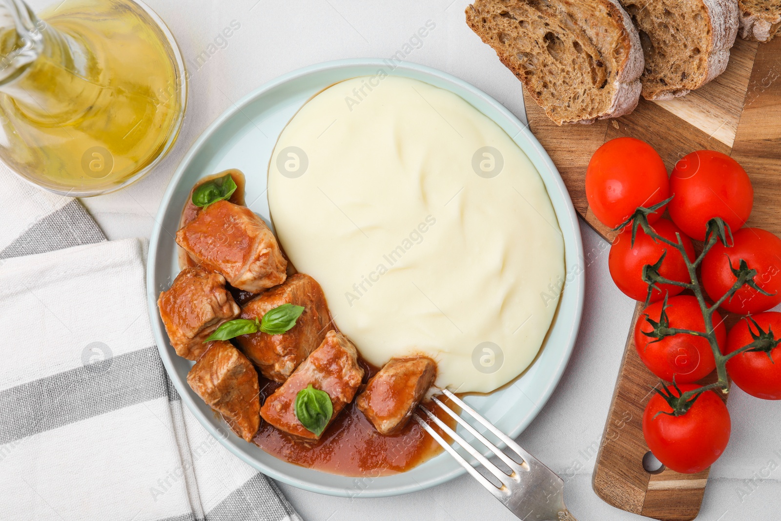 Photo of Delicious goulash served with mashed potato on white table, flat lay