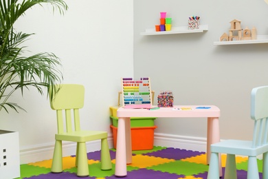 Photo of Stylish playroom interior with table and chairs