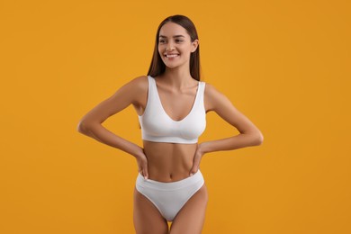 Young woman in stylish white bikini on orange background