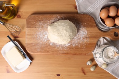 Photo of Fresh dough sprinkled with flour and other ingredients on wooden table, flat lay