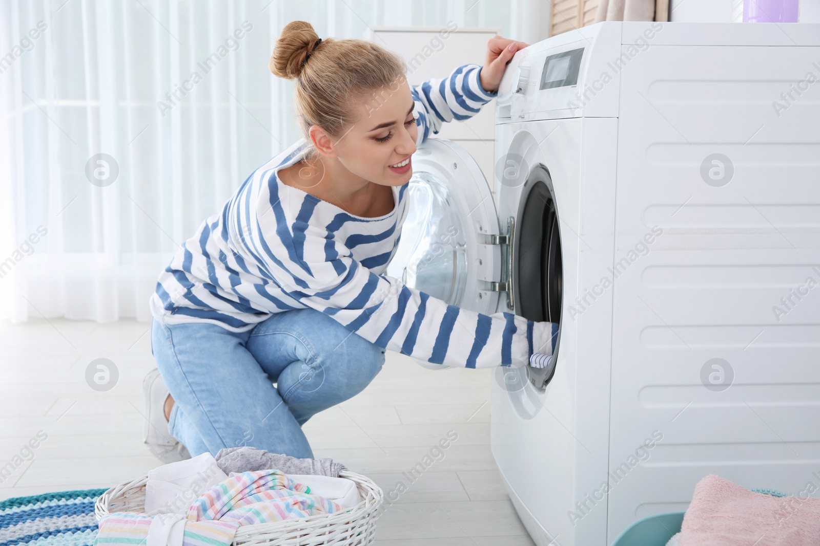 Photo of Young woman using washing machine at home. Laundry day