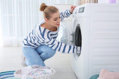 Young woman using washing machine at home. Laundry day