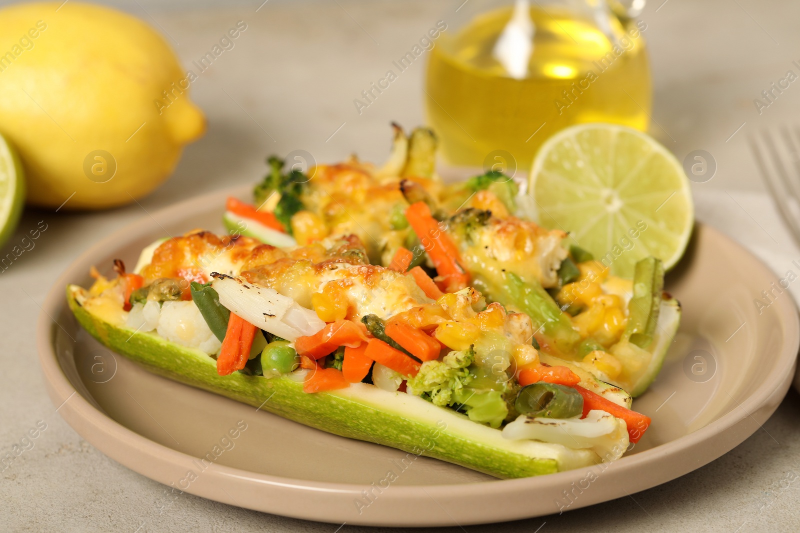 Photo of Baked stuffed zucchinis served with lime on light table, closeup