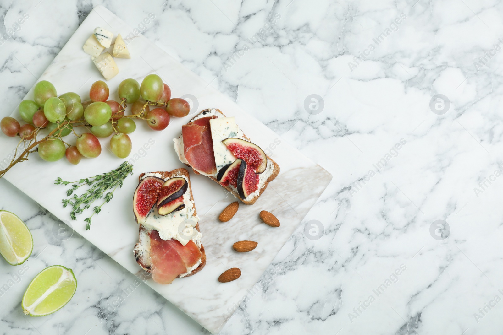 Photo of Sandwiches with ripe figs and delicious products on marble table, top view. Space for text