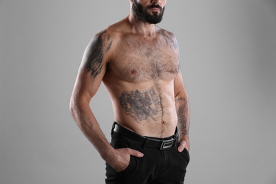 Photo of Tattooed man on grey background, closeup view
