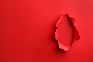 Hole in red paper on color background, space for text