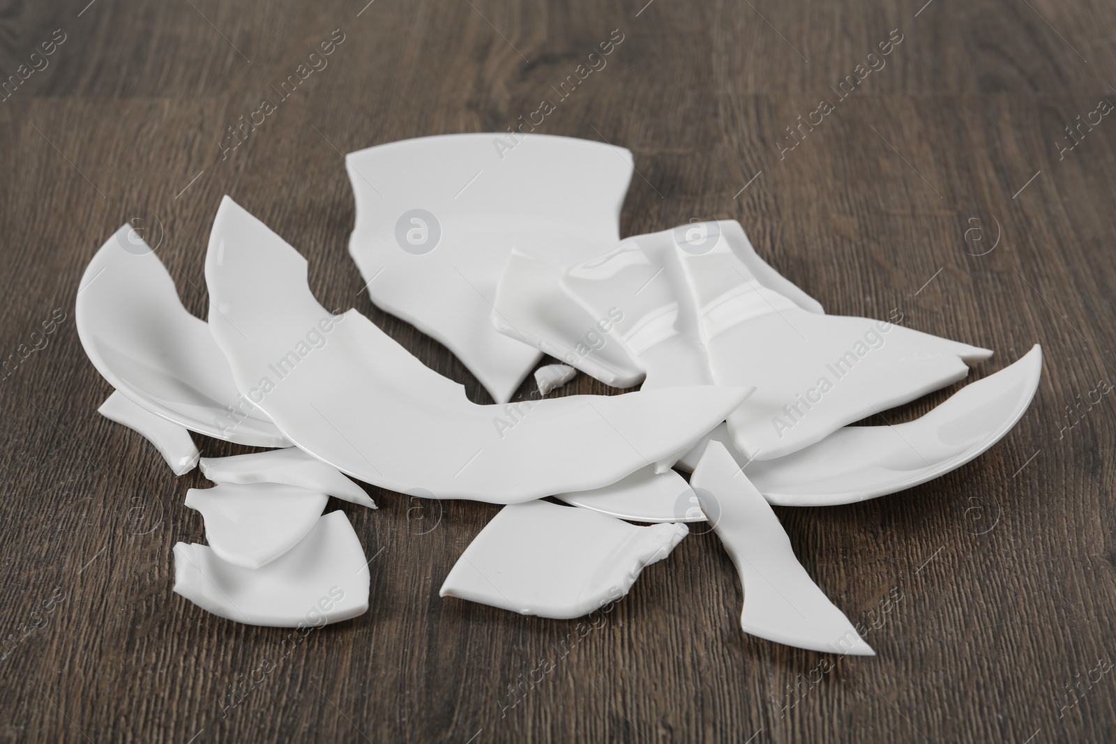 Photo of Pieces of broken ceramic plate on wooden floor